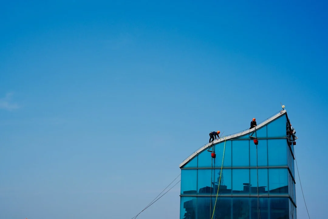 High-rise window washers in safety gear cleaning a skyscraper facade.